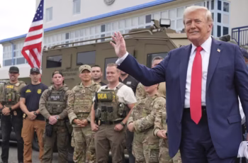 National Guard troops carrying rifles stand watch near Union Station in Washington, D.C., as protesters gather nearby, highlighting rising tensions after President Trump authorized some units to be armed during demonstrations.