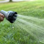 "Oscillating garden sprinkler watering green lawn showing water spray pattern for efficient yard irrigation"